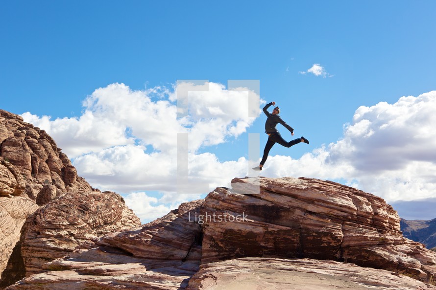 man leaping over a mountain