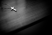 Cross pendant and necklace on a wood table.