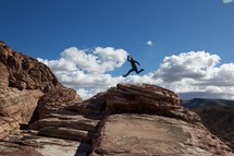 man leaping over a mountain