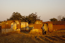 Men standing outdoors against a home in ruins in Malawi, Africa.
