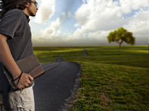 teen boy holding a bible heading down the open road