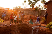 Children playing outdoors in red mud in Malawi, Africa. 