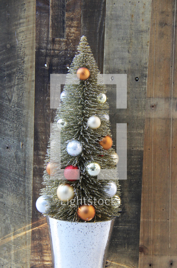 Small decorated Christmas tree against a wooden background