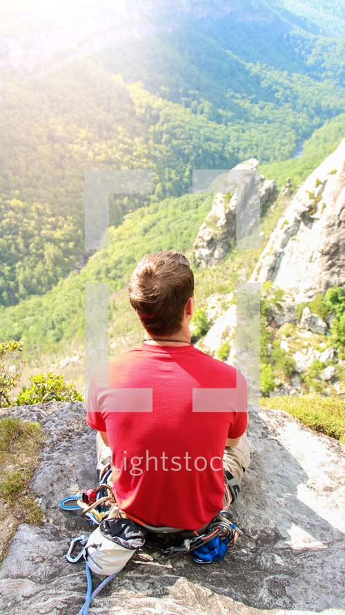 man siting on a rock on a mountain under sunlight 