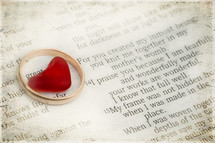Heart in a gold wedding band on top of a Bible open to Psalm 139.