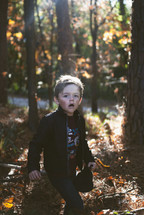 young boy walking through a forest 