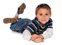 A boy laying on his stomach with legs crossed.