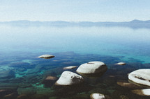 stones in shallow water and mountains in the distance 