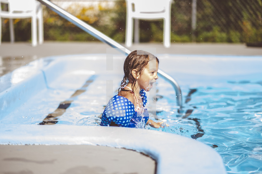 a little girl swimming in a pool 