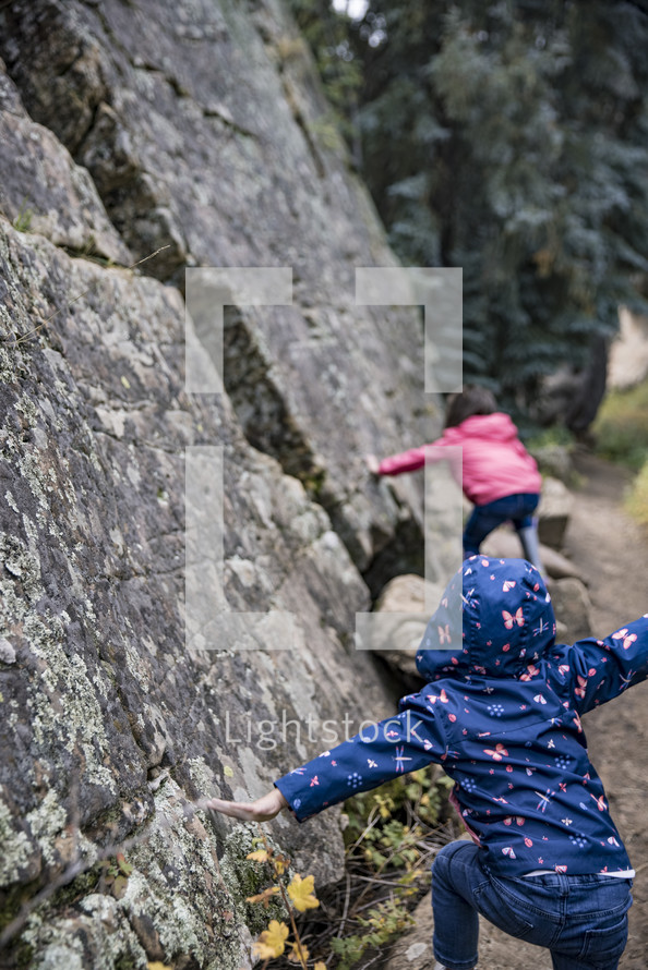 kids pretending to climb a rock cliff 