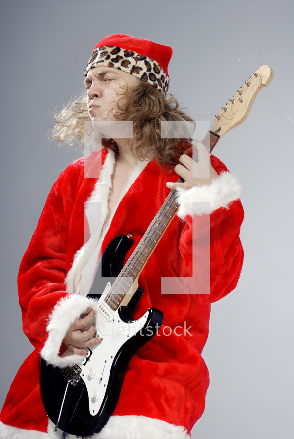 a man in a Santa Suit jamming on a guitar 