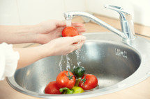woman washing vegetables in a sink 