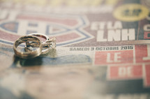 engagement ring and wedding bands on newspaper 