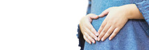 A pregnant mother with heart shaped hands on her belly 