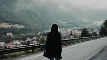 a woman walking down a foggy mountain road 