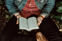a young man sitting reading a Bible in his lap 