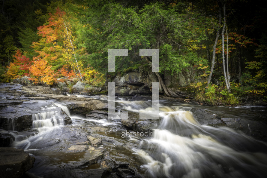 Moving water in rocky stream with fall trees