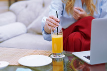 woman drinking orange juice and working in a lobby 