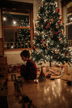 a boy child playing under a Christmas tree 
