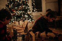 children playing with toys around a Christmas tree 
