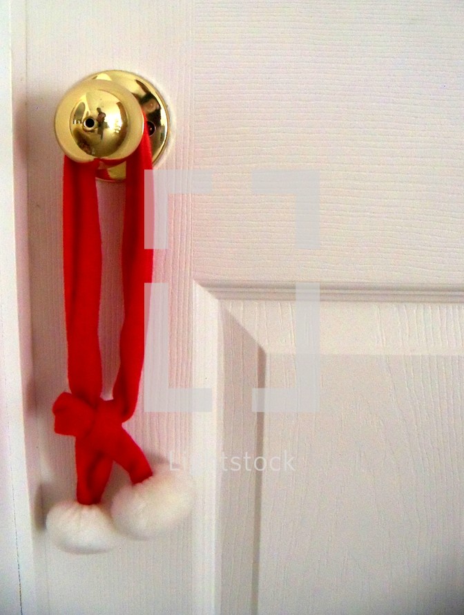 Christmas decor hung on a doorknob to decorate a home for Christmas to add warmth, color and fun for the holidays. 