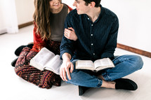 a couple sitting on the floor reading Bibles 