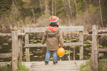 a toddler on a dock holding a balloon 