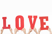 word love in red held up by hands 