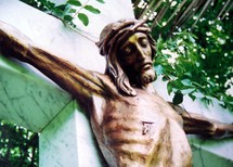 A bronze sculpture of Jesus on the cross showing where he was pierced with a spear and hung on the cross to die for the sins of mankind. Jesus is shown here on a marble cross and a bronze statue depicting Jesus wearing a crown of thorns and nails in his feet and hands. 