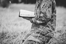 Christian soldier in a field praying holding a Bible 