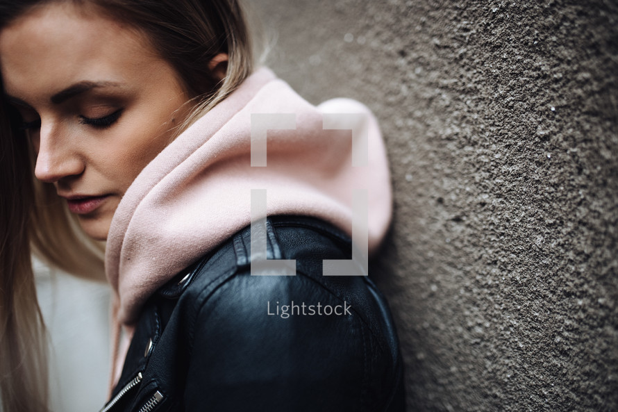 a woman in a leather jacket and pink hoodie