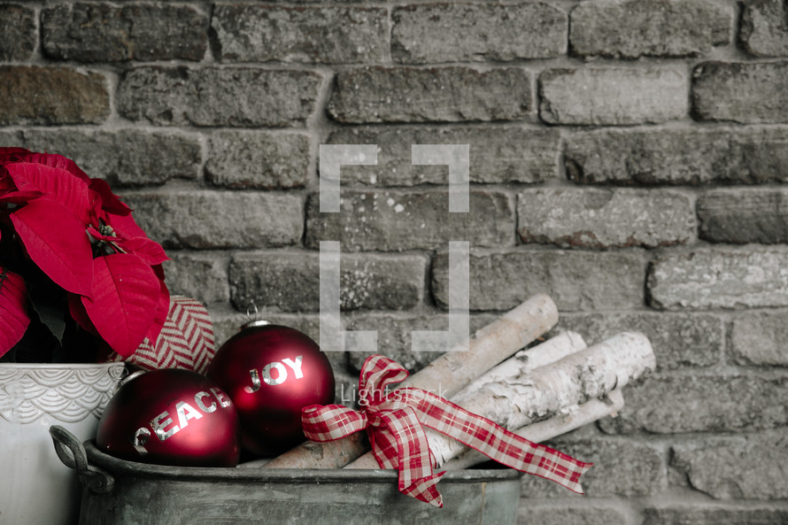 An arrangement of Christmas decorations against the backdrop of a gray brick wall.