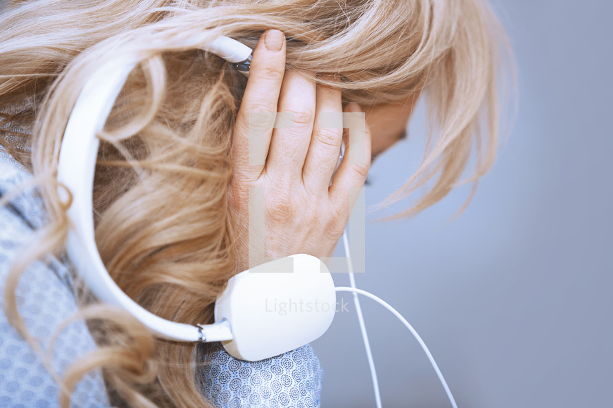 a woman holding headphones to hear ear 