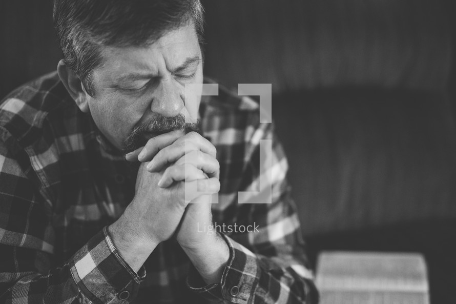 a man sitting on a couch praying 