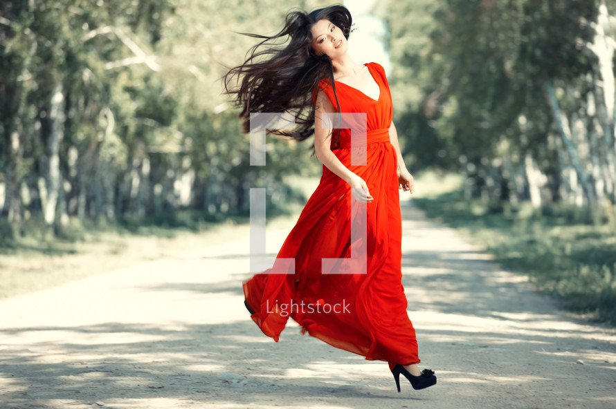 a woman jumping in a red dress 