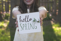 little girl holding a Hello spring sign 