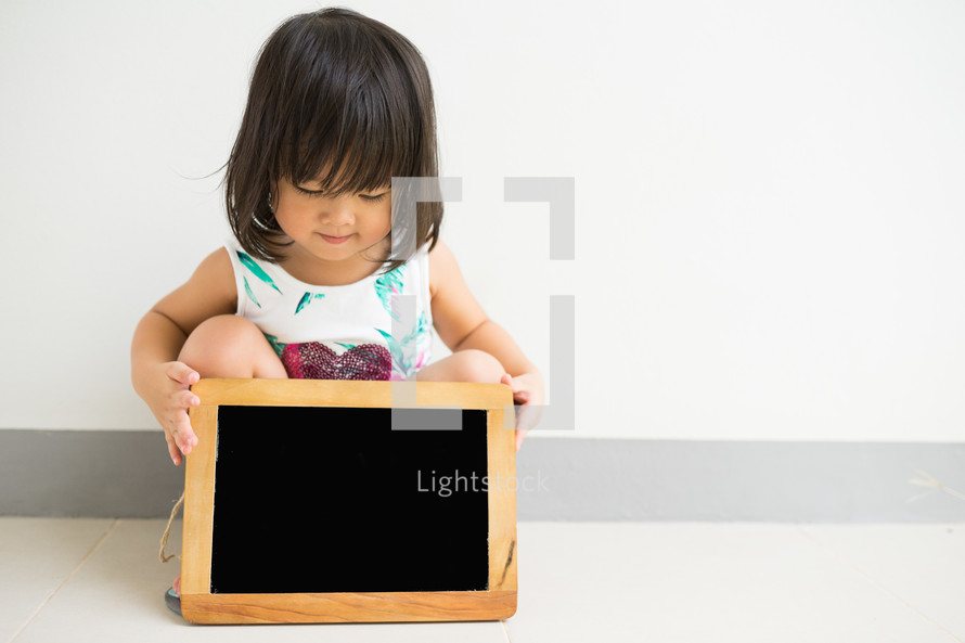a little girl holding a chalkboard 