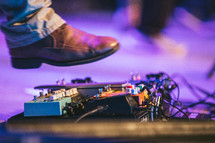 a man's foot on a guitar pedal on stage 