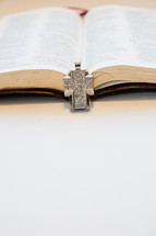 diamond studded cross necklace lying on the pages of a Bible
