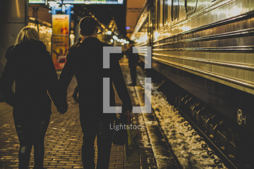 a couple walking holding hands in a subway