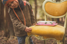 a child  and yellow chair with books on it in a forest 