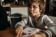 boy coloring on a coloring page at home 