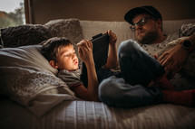 father and son reading together from a tablet 
