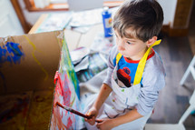 a child painting a cardboard box 