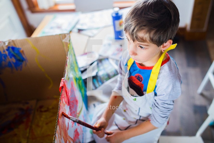 a child painting a cardboard box 