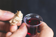 communion wine cup and bread in a man's hands 