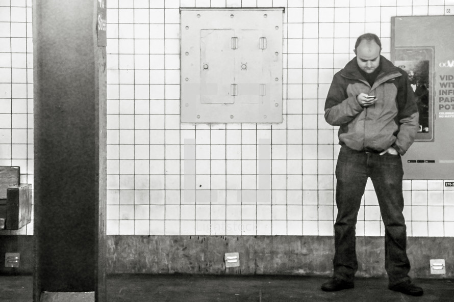 a man looking at his cellphone in a subway 