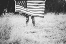 soldier in a field holding an American flag 