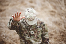 Christian soldier kneeling in a field with hand raised 