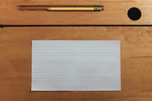 blank paper and pencil on a student desk 